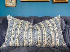 a blue couch with two framed pictures on the wall behind it and a decorative pillow