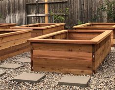 several wooden planters are lined up on the gravel