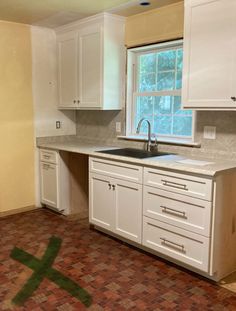 an empty kitchen with white cabinets and tile flooring in the middle of the room