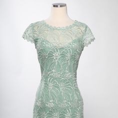 a green dress on a mannequin head stand