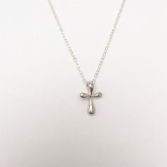 A gorgeous tiny and simple, Sterling Silver cross hangs delicately from a Sterling Silver chain. This small, slightly puffy cross has softly rounded edges and is super smooth. Available in Sterling Silver or Gold Vermeil. A beautiful keepsake piece of jewelry or gift for a baptism or dedication that will last a lifetime. - Pendant - Sterling Silver or Gold Vermeil - 13mm x 9mm (Made in the USA) - Chain + components - Sterling Silver or 14K Gold-Fill - Clasp - Sterling Silver or 14K Gold-filled l Affordable Silver Cross Pendant Jewelry, Small Silver Cross Necklace, Silver Cross Necklace With Delicate Chain, Minimalist Hypoallergenic Cross Jewelry, Silver Charm Necklace With Cross Pendant, Silver Charm Necklace With Cross Pendant And Delicate Chain, Minimalist Cross Pendant Necklace For First Communion, Minimalist Silver Cross Pendant Charm Necklace, Minimalist Silver Charm Necklace With Cross Pendant