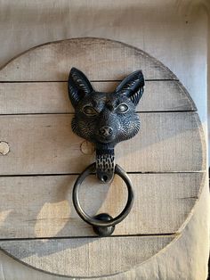 an animal head mounted on the side of a wooden door knocker with a metal ring