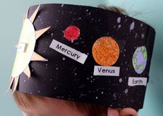 a child wearing a paper crown with planets on it