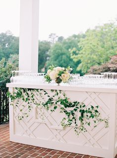 an outdoor bar decorated with flowers and greenery