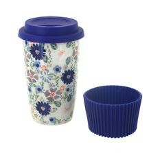 a coffee cup with a blue lid sitting next to a flowered ceramic cup holder