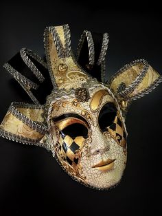 Whimsical and colorful this gold black tone Jester mask is inspired by the traditional Venetian Carnival. This mask features vibrant colors, intricate designs, and exaggerated features to convey a sense of playfulness and jest. Fantasy Full Face Mask For Masquerade, Black Full Face Carnival Masks, Fantasy Gold Masks And Prosthetics For Halloween, Gold Venetian Mask For Halloween, Gold Fantasy Festival Masks And Prosthetics, Gold Costume Masks For Halloween, Venetian Gold Masquerade Mask For Halloween, Gold Venetian Masquerade Mask For Halloween, Fantasy Masks And Prosthetics For Carnival Festival