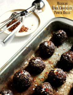 a pan filled with chocolate truffles on top of a wooden table next to utensils