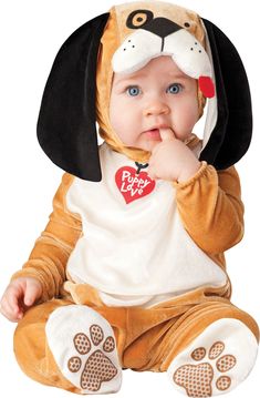 a baby in a dog costume sitting on the ground with his hand under his chin