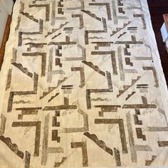 a bed with a white and brown quilt on top of it