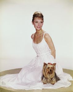 a woman in a white dress sitting next to a dog