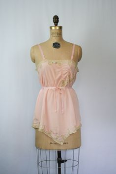 "Vintage 1920s pink silk crepe embroidered floral lace chemise Beautiful lace inset neckline with a sweet ribbon flower Pick stitch embroidery detail on front bust line and more beautiful lace Lace trimmed hem Fabric tie that is attached at back waist and can be worn tied around waist or in a simple bow at back Silk ribbon straps Crotch has been undone so it can be worn as a camisole Pull on MEASUREMENTS: taken flat Fits like a Small Bust: up to 36\" Waist: up to 38\" Hips: up to 46\" Strap Leng Delicate Lace Trim Camisole For Daywear, Feminine Sheer Camisole For Daywear, Vintage Lace Trim Camisole For Spring, Vintage Slip Dress For Wedding Night, Vintage Lace Camisole For Spring, Vintage Pink Slip Dress For Daywear, Pink Lace Trim Camisole In Coquette Style, Flirty Lace Trim Slip Dress For Daywear, Pink Lace Trim Slip Dress For Daywear