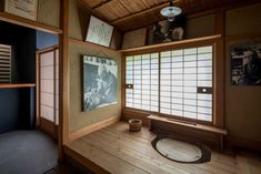 an empty room with wooden floors and pictures on the wall, including a lantern hanging from the ceiling