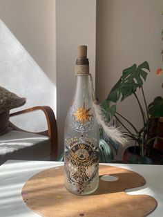 a glass bottle sitting on top of a wooden table next to a potted plant