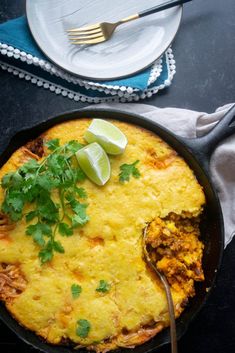 a skillet filled with mexican food on top of a table next to a plate