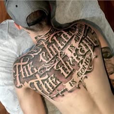 a man laying on top of a bed covered in lots of tattoos and writing next to his head