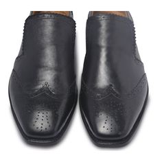 To find that perfect blend of smart casual in footwear, look no further than this pair of black brogue wingtip slip-on leather loafers. You can go sockless in them with jeans on a casual night out with friends or wear them with a trendy, sleek suit for a formal event. Wingtips are a brogue with details on the extended toecap that add a dash of personality to your attire. Slip into these easy to wear stylish shoes for casual or formal events to look more stylish than ever. Some of its features include: Slip-On Shoes Wingtip with Bull Brogue design Perforations and pinking on a top of shoe vamp The edges of the shoe back stay also have perforations and pinking Comfortable in-sole Available in classic black and tan tones, this leather footwear is a must-have for all tasteful fashion lovers ou Black Cap Toe Semi-formal Loafers, Leather Wingtip Slip-ons For Business, Classic Black Slip-ons With Brogue Detailing, Slip-on Leather Shoes With Brogue Detailing For Business Casual, Black Textured Sole Slip-ons For Business Casual, Classic Black Slip-ons With Stitched Sole, Black Monk Strap Shoes With Wingtip And Rubber Sole, Black Wingtip Monk Strap Shoes With Rubber Sole, Casual Wingtip Slip-ons For Business