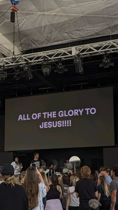 a group of people standing in front of a large screen with the words all of the glory to jesus on it