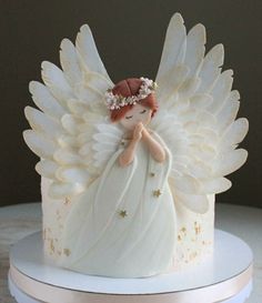 a white cake with an angel decoration on top