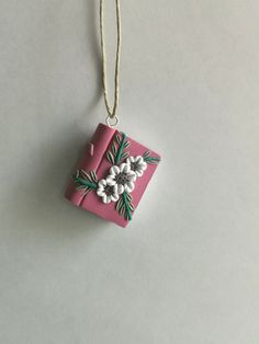 This cute-as-a-button bookstack will look lovely as a necklace pendant or charm.  I make each item by hand with high quality polymer clay. The flowers are individually made, no molds have been used. The bookstacks are about ¾ inch (w) x ¾ inch (L) // 1.9cm x 1.9cm.  This item is one-of-a-kind as the colour blends are unique.  Pendant only. Please be aware that your monitor may not depict the color of the pieces accurately, as all monitor colours are calibrated differently. Whimsical Charm Necklace For Gifts, Whimsical Charm Necklace For Gift, Pink Charm Necklace For Gifts, Small Charm Necklaces For Gifts, Handmade White Charm Necklaces For Birthday Gift, Nickel-free Square Pendant Charm Necklace As Gift, Unique Charm Necklace As Gift, Whimsical Personalized Necklaces For Gifts, Pink Spiritual Charm Necklace For Gift