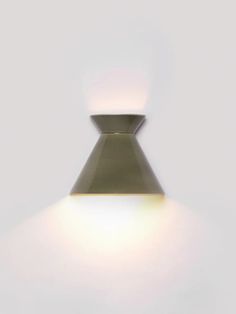 a light that is on in the middle of a white wall with a shadow from it