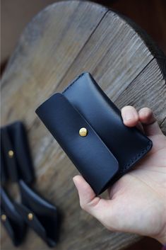 a hand holding a black wallet on top of a wooden table