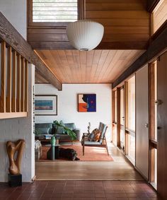 a living room filled with furniture next to a wooden ceiling mounted above a doorway on top of a hard wood floor