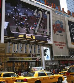 taxi cabs are driving down the street in front of a large advertisement for forever