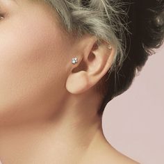 a close up of a person's face wearing ear piercings and looking off to the side