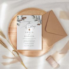 the wedding stationery is displayed on top of a wooden plate next to an envelope