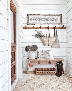 a wooden bench sitting in front of a white wall next to a potted plant