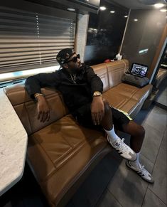 a man sitting on top of a brown leather couch