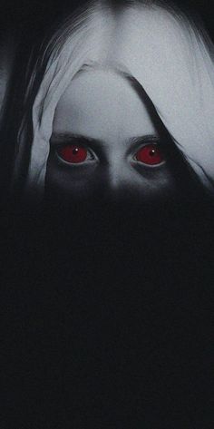 a woman's face with red eyes in the dark