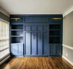 an empty room with dark blue cabinets and wood flooring is pictured in this image