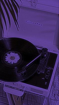 an old record player sitting on top of a table next to a potted plant