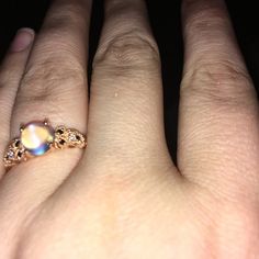 a woman's hand with a ring on it that has a rainbow colored stone in the middle