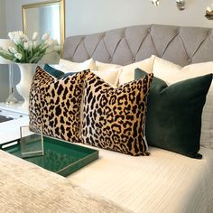 a bed with two leopard pillows on top of it and a green tray in the middle