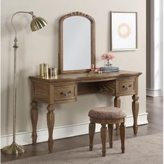 a wooden vanity with mirror and stool in a room next to a lamp on the wall