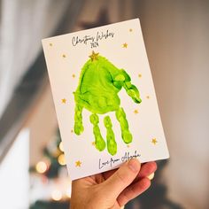 someone holding up a card with a green handprint on it