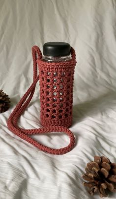 a red crocheted bag sitting on top of a bed next to pine cones