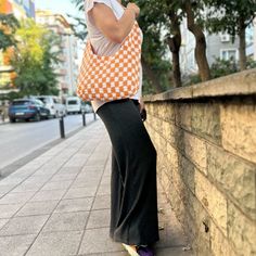 a woman leaning against a brick wall with her hand on her hip