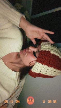 a woman wearing a red, white and blue crocheted hat with her hand on the top of her head