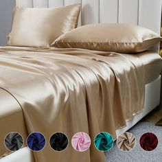 a bed with four different colors of sheets and pillows