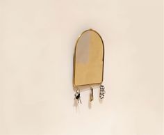 a mirror hanging from the side of a wall next to two small keys and a pair of scissors