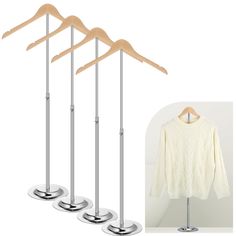 three wooden clothes hangers and four white sweaters on metal stands with wood tops