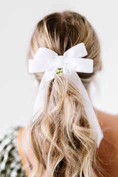 the back of a woman's head with a white bow in her hair