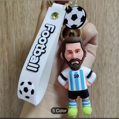 a person holding a keychain with a soccer player on it's face