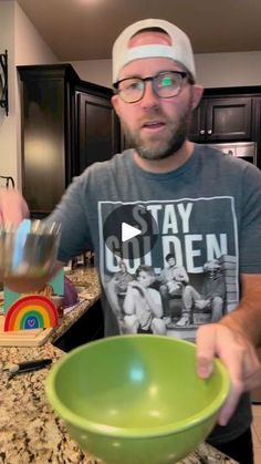 a man in glasses is mixing something in a green bowl