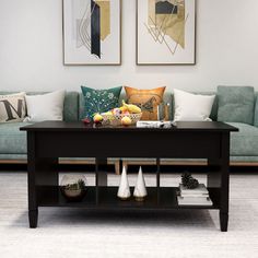 a living room with two paintings on the wall and a coffee table in front of it