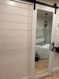 an open door leading to a bathroom with a bathtub and mirror on the wall