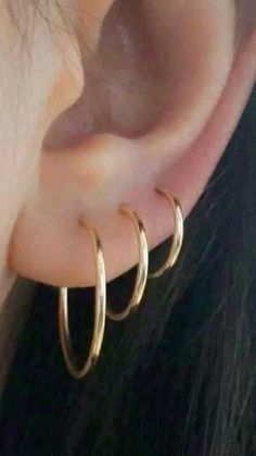 a woman wearing two gold hoop earrings on her ear